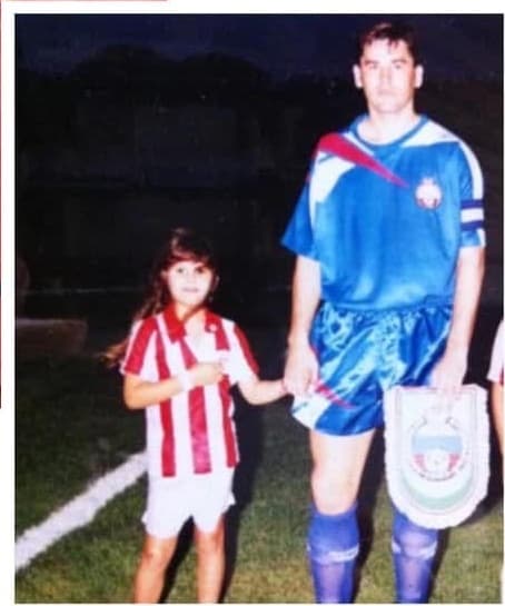 Carla Larini na infância ao lado do pai em um campo de futebol