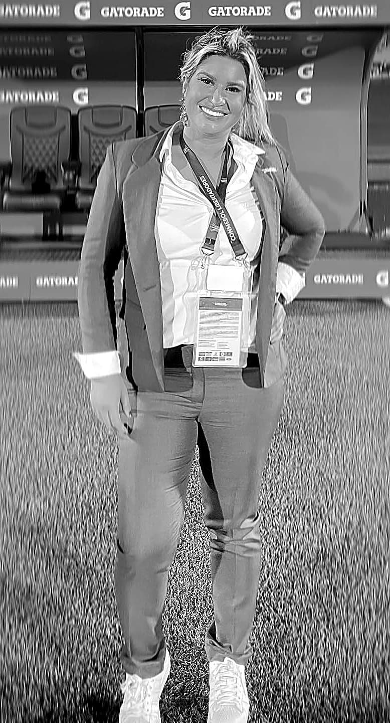 Carla Larini à beira do gramado com credencial da Conmebol
